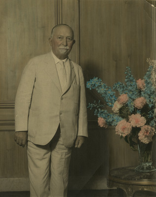 John H. Kellogg posing beside flower arrangement